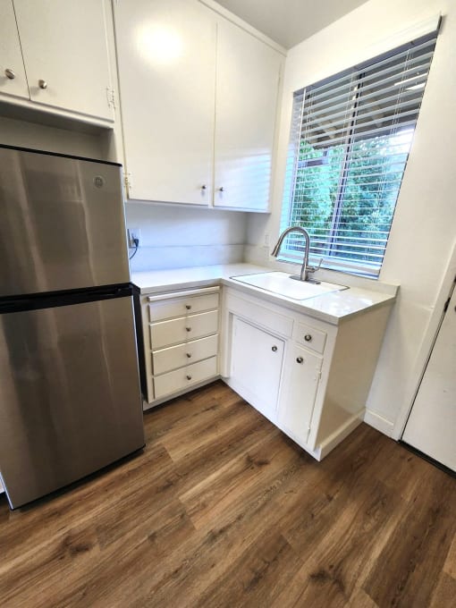 a small kitchen with white cabinets and a stainless steel refrigerator