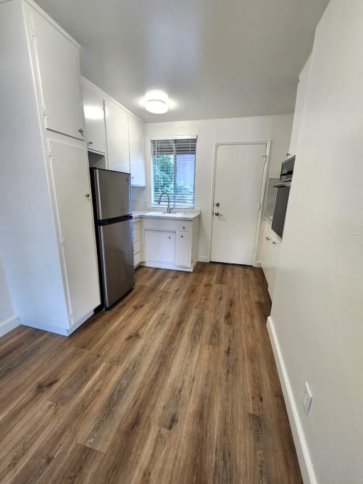 an empty kitchen with a refrigerator and a sink
