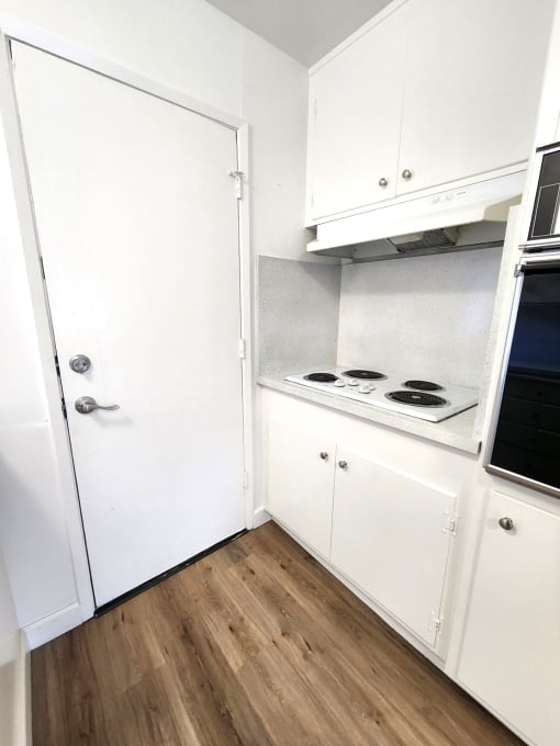 a small bathroom with white cabinets and a wood floor
