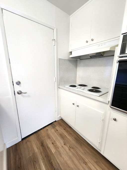 an empty kitchen with white cabinets and a stove top oven