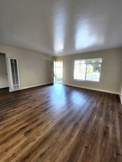 an empty living room with wood floors and a window
