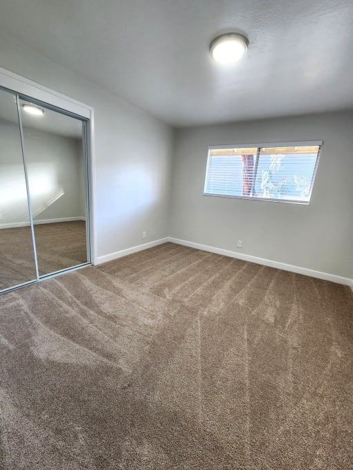 an empty room with carpet and a mirrored closet