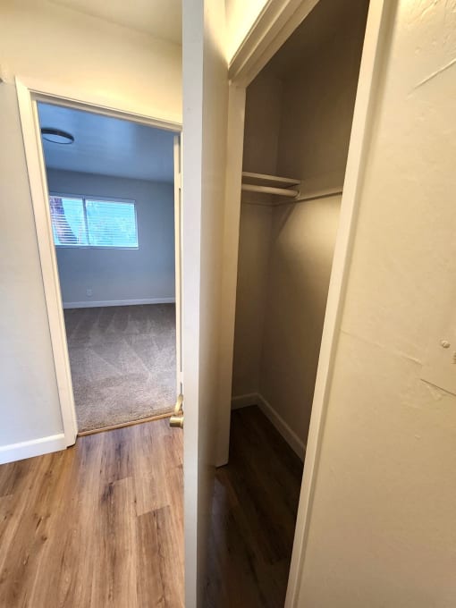 an empty hallway with a door open to a closet and a window