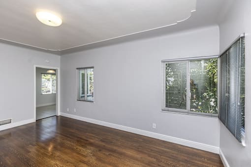 an empty living room with wood floors and a large window
