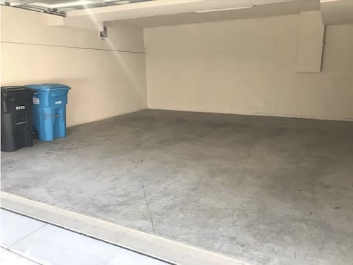 a garage with a concrete floor and two trash cans