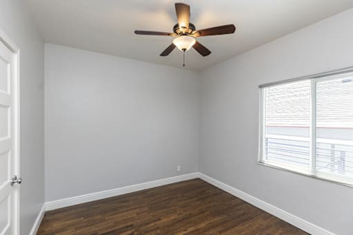 an empty room with a ceiling fan and a window