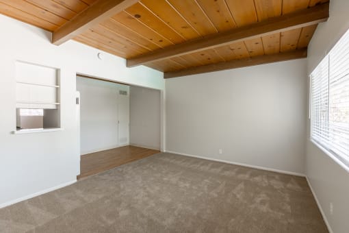 an empty room with a wooden ceiling and carpet