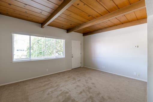 an empty living room with a large window and carpet