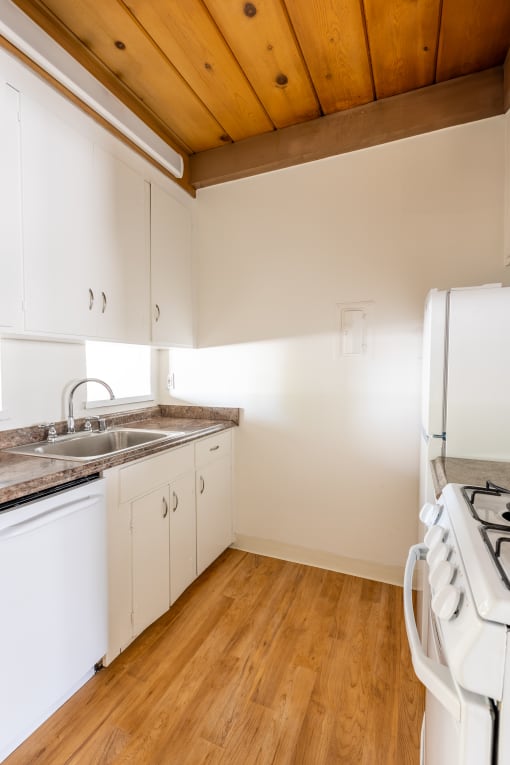 a small kitchen with white cabinets and a wooden floor