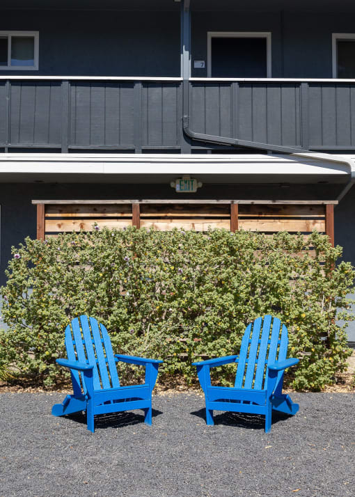 two blue chairs sitting in front of a building