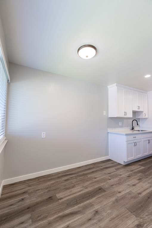 A kitchen with white cabinets and a wooden floor.