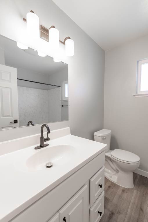 A white bathroom with a sink, toilet, and mirror.