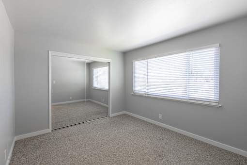 A room with a carpeted floor and a large mirror on the wall.