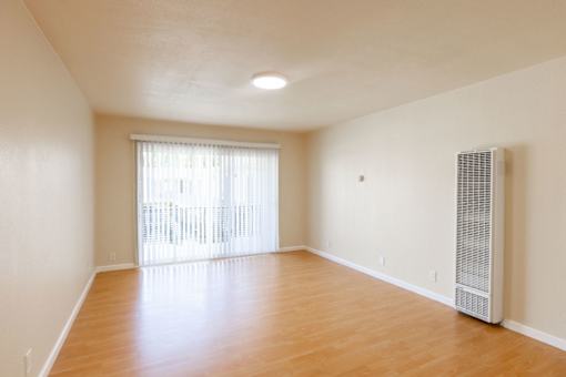 an empty living room with wood flooring and a window