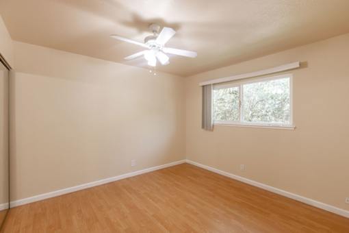 an empty room with a ceiling fan and a window