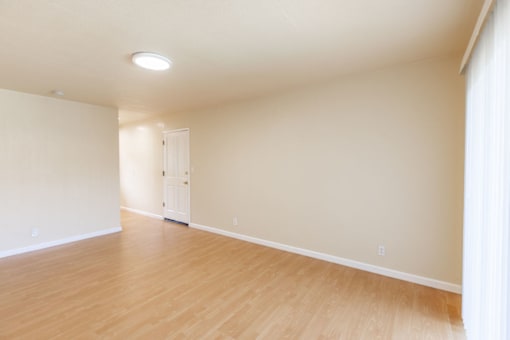 an empty living room with wood floors and a white door