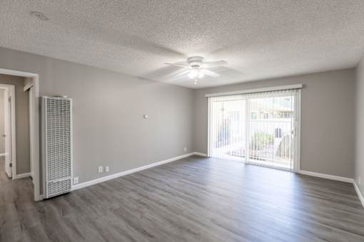 an empty living room with a ceiling fan and a window