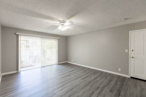 an empty living room with wood floors and a ceiling fan