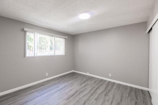 an empty living room with wood floors and a window