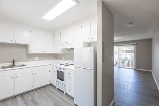 an empty kitchen with white cabinets and a window