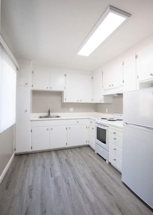 an empty kitchen with white cabinets and white appliances