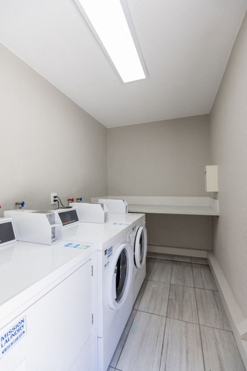 a washer and dryer in a laundry room with wood floors and a window