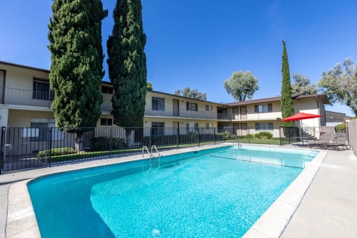 a swimming pool in front of an apartment building with a pool
