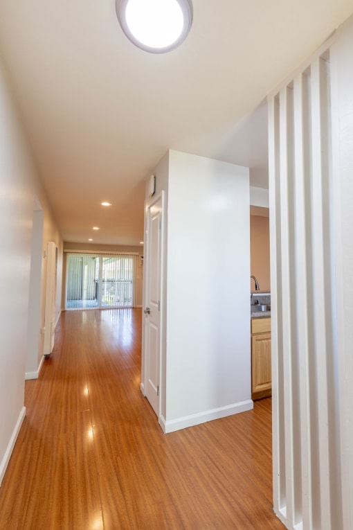 a living room and dining room with white walls and wood floors