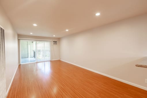an empty living room with wood floors and a sliding glass door