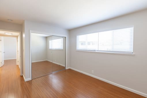 an empty living room with wood floors and a large window