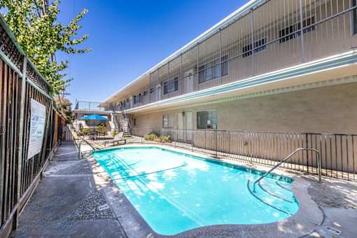 a swimming pool is next to a building with a fence