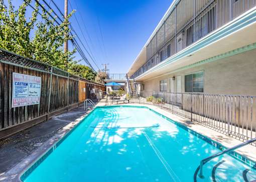 the pool is next to a building with a blue pool