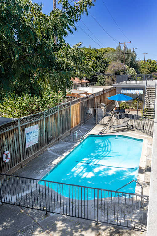 a swimming pool in the backyard of a house with a fence around it