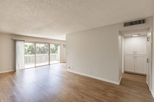 the living room and dining room of an empty house with wood floors and a balcony