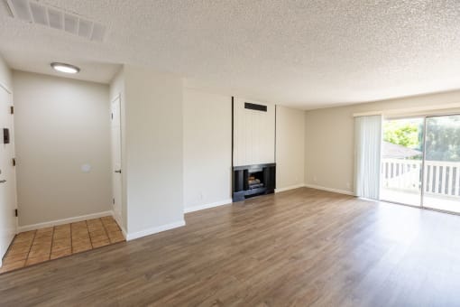 an empty living room with a wood floor and a fireplace