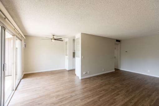 an empty living room with wood floors and a ceiling fan