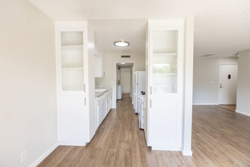 a renovated living room and kitchen with white cabinets and wood floors