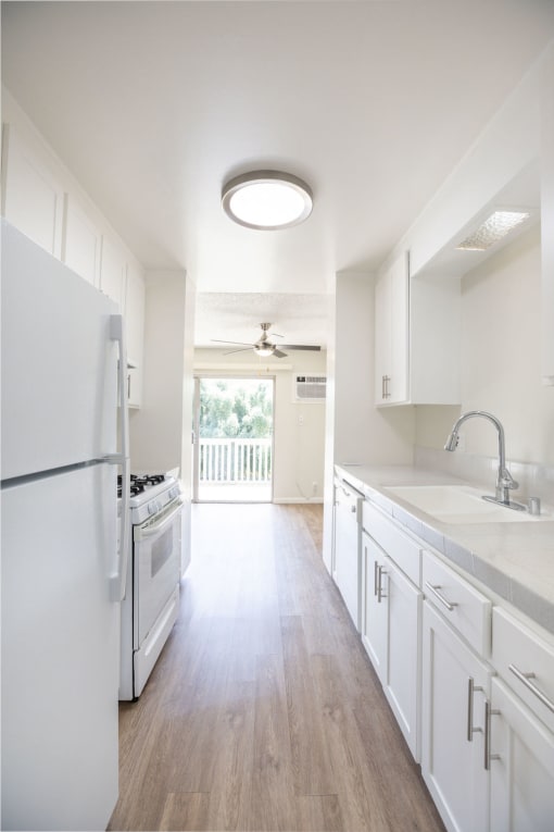 an empty kitchen with white cabinets and a white stove and refrigerator