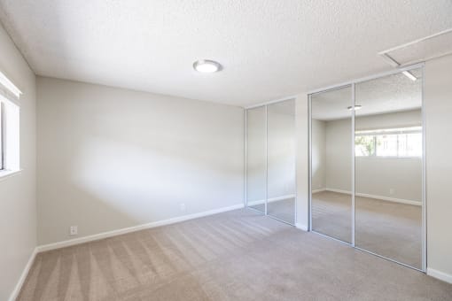 an empty living room with mirrored closet doors