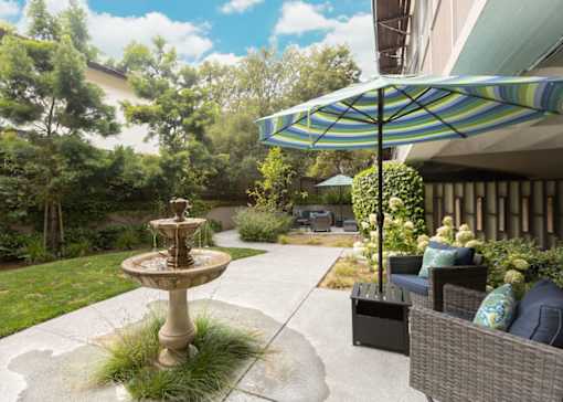 A patio with a fountain and a wicker sofa.