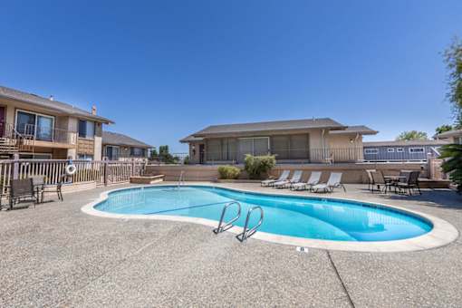 a swimming pool with chairs around it in front of a house