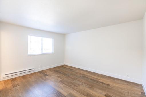 an empty room with wood flooring and a window