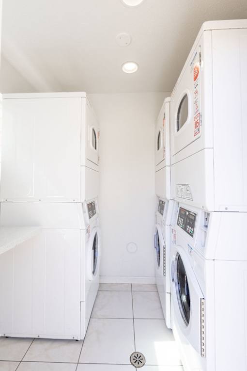 a white laundry room with white washes and dryers