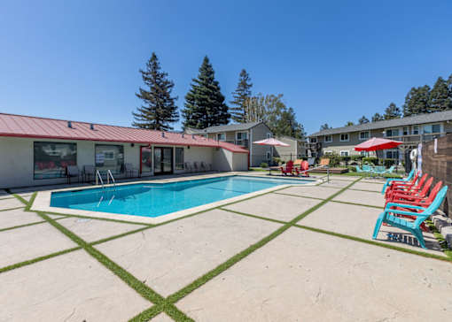a pool with chairs and umbrellas next to a building