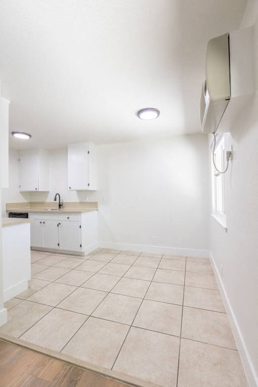 an empty kitchen with white cabinets and a tiled floor