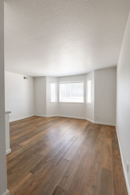 an empty living room with hardwood floors and a window