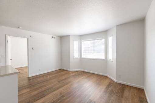 an empty living room with wood flooring and a window