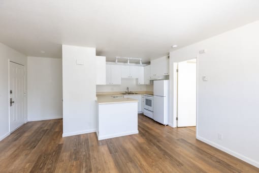 an empty kitchen with white cabinets and a wood floor