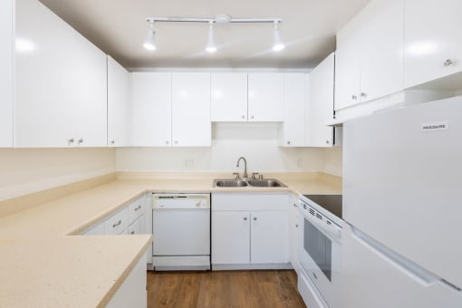 a kitchen with white cabinets and appliances and a sink