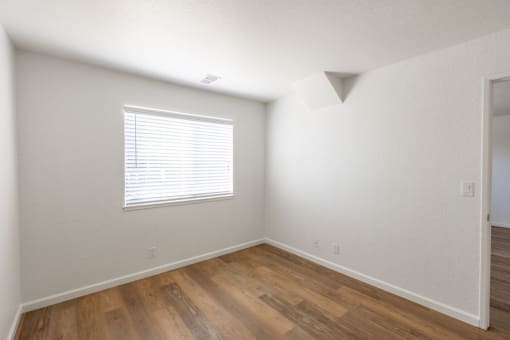 an empty room with wood floors and a window